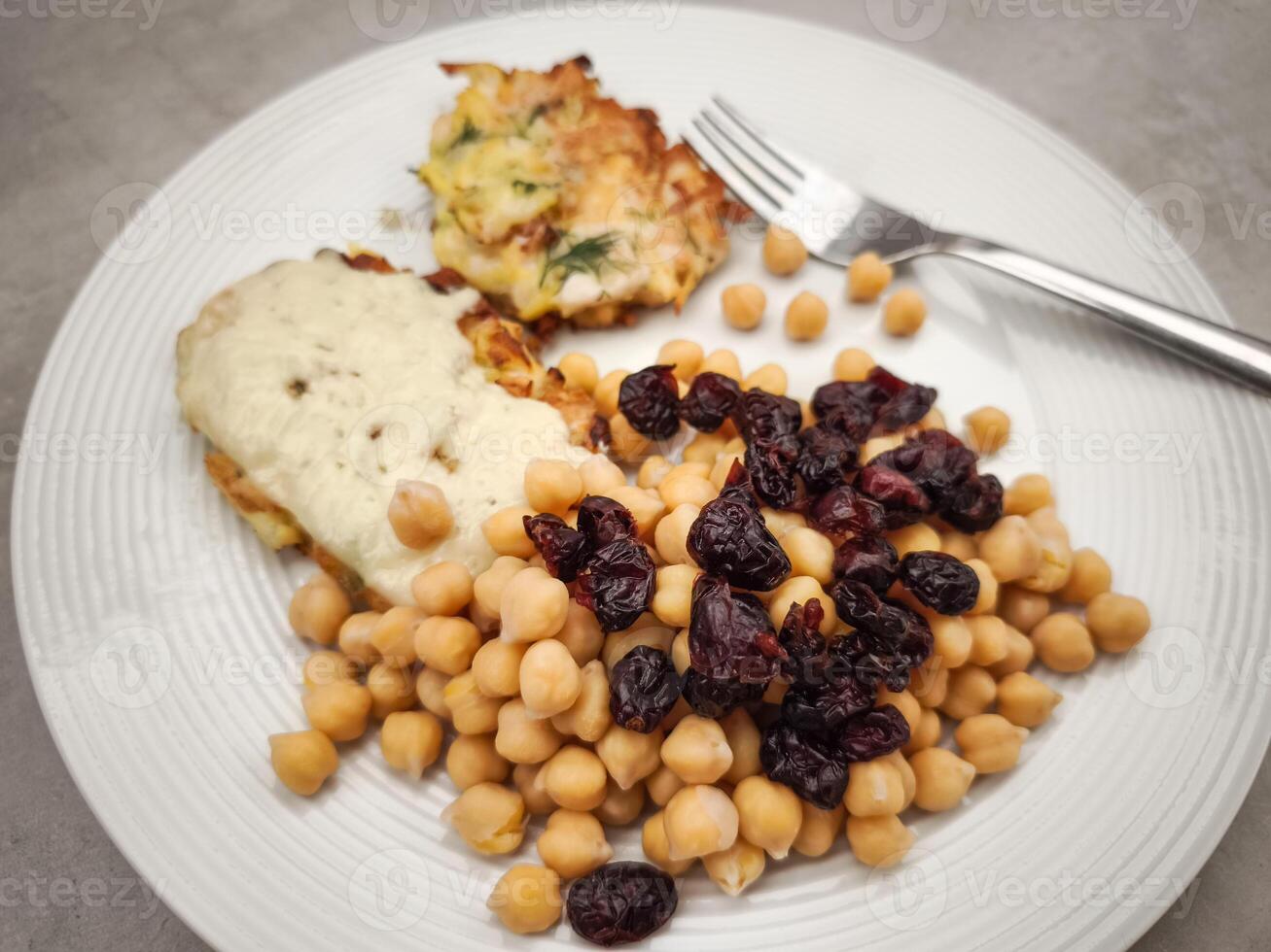 Golden potato pancakes topped with chickpeas, cranberries, drizzling creamy yogurt sauce on rustic wooden surface Galentines day photo