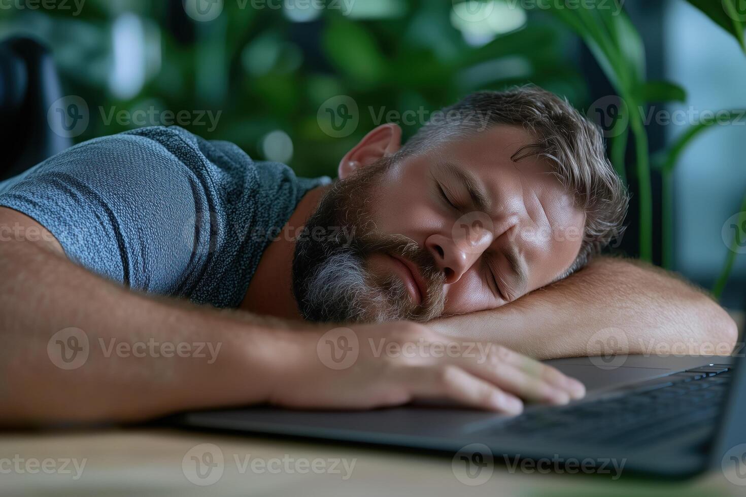 Man sleeping in front of laptop at workplace. Young man sleeping on a laptop. photo