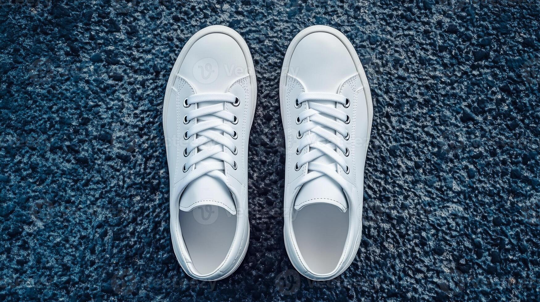 Fresh white sneakers positioned on textured dark surface during daylight photo