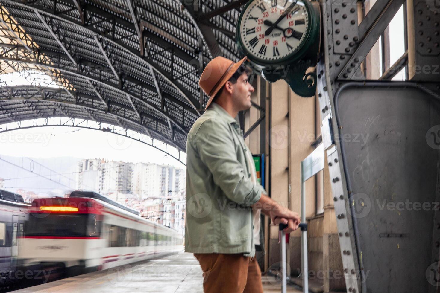 latin Tourist waiting for train departure at railway station under clock photo