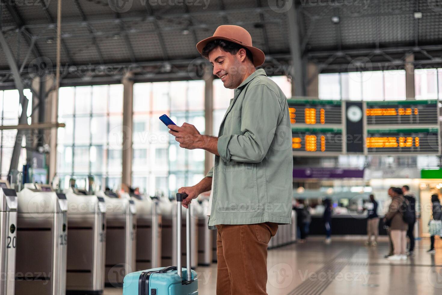 latin Tourist using smartphone while waiting for train at station near panel information photo