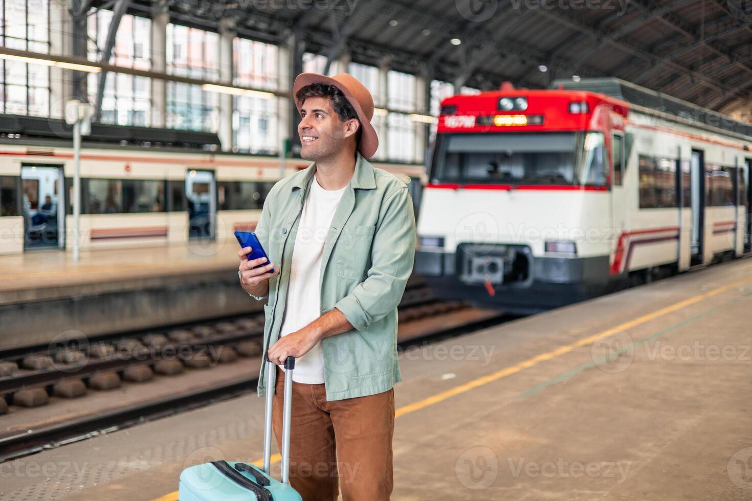 latin Tourist holding smartphone and suitcase is waiting for train at station photo