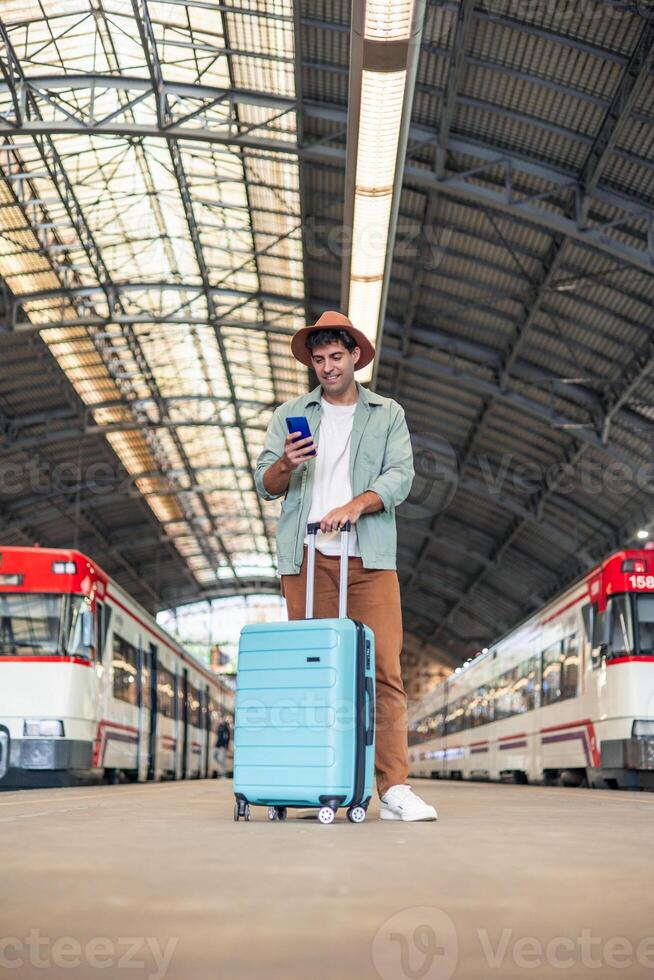 vertical latin Tourist using smartphone while waiting for train in station photo