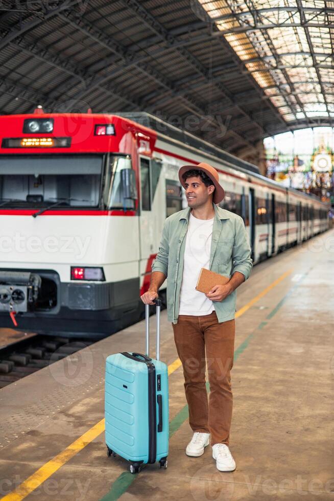 vertical latin Tourist walking with suitcase and book in train station photo