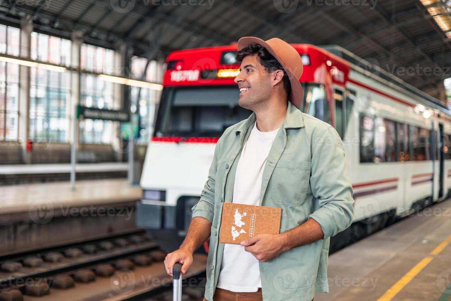 happy latin Tourist holding nook and suitcase waiting for train at station photo