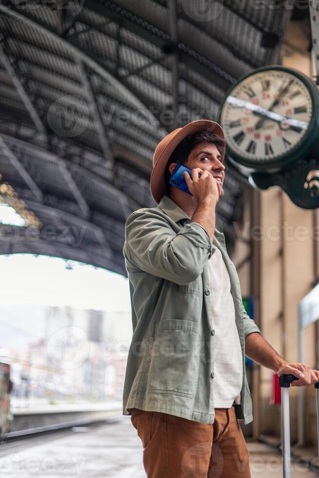 vertical latin Tourist talking on the phone waiting for the train at the station photo