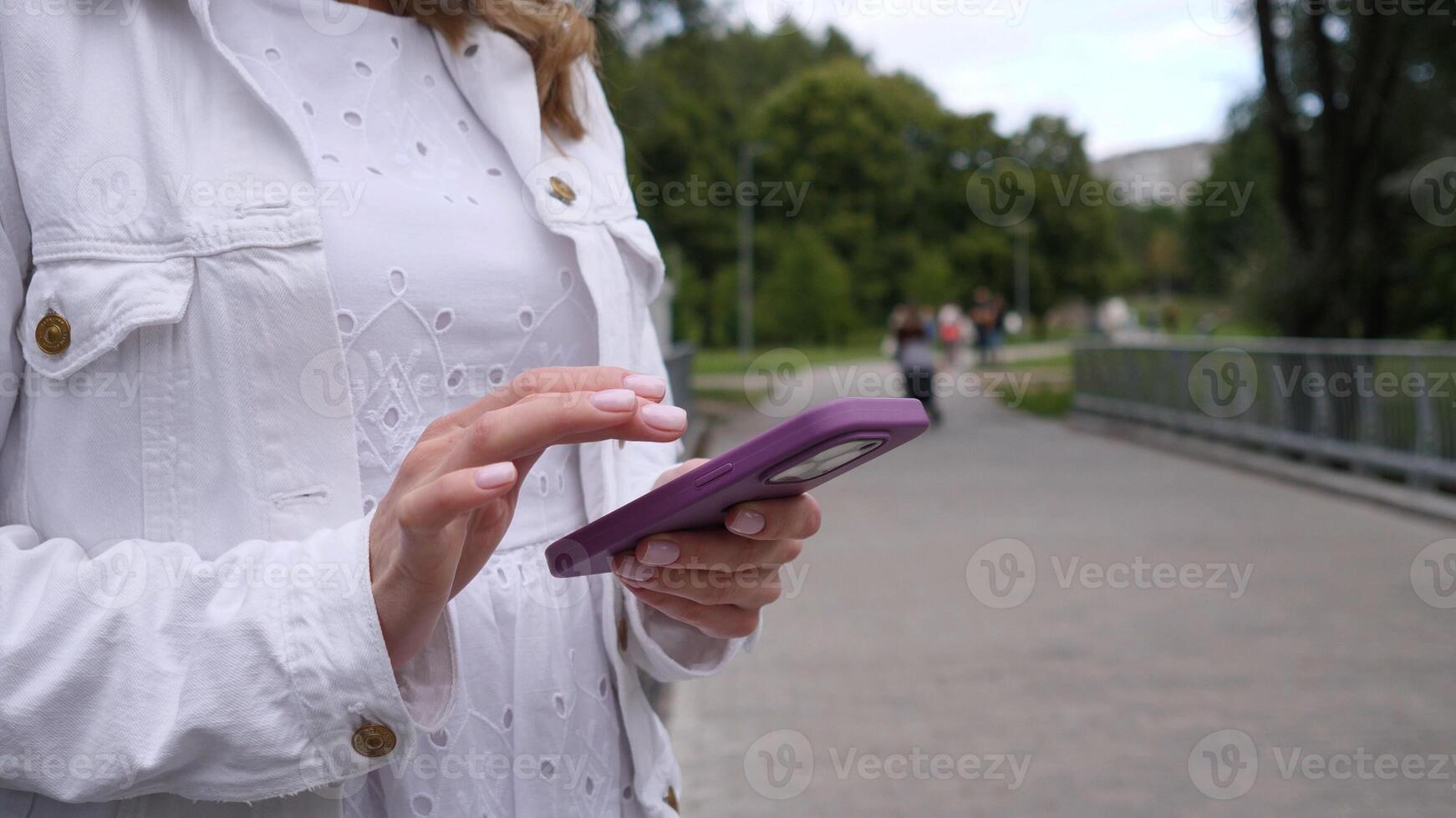 A young adult is engaged in an activity with a mobile device while relishing the tranquil atmosphere of a park photo