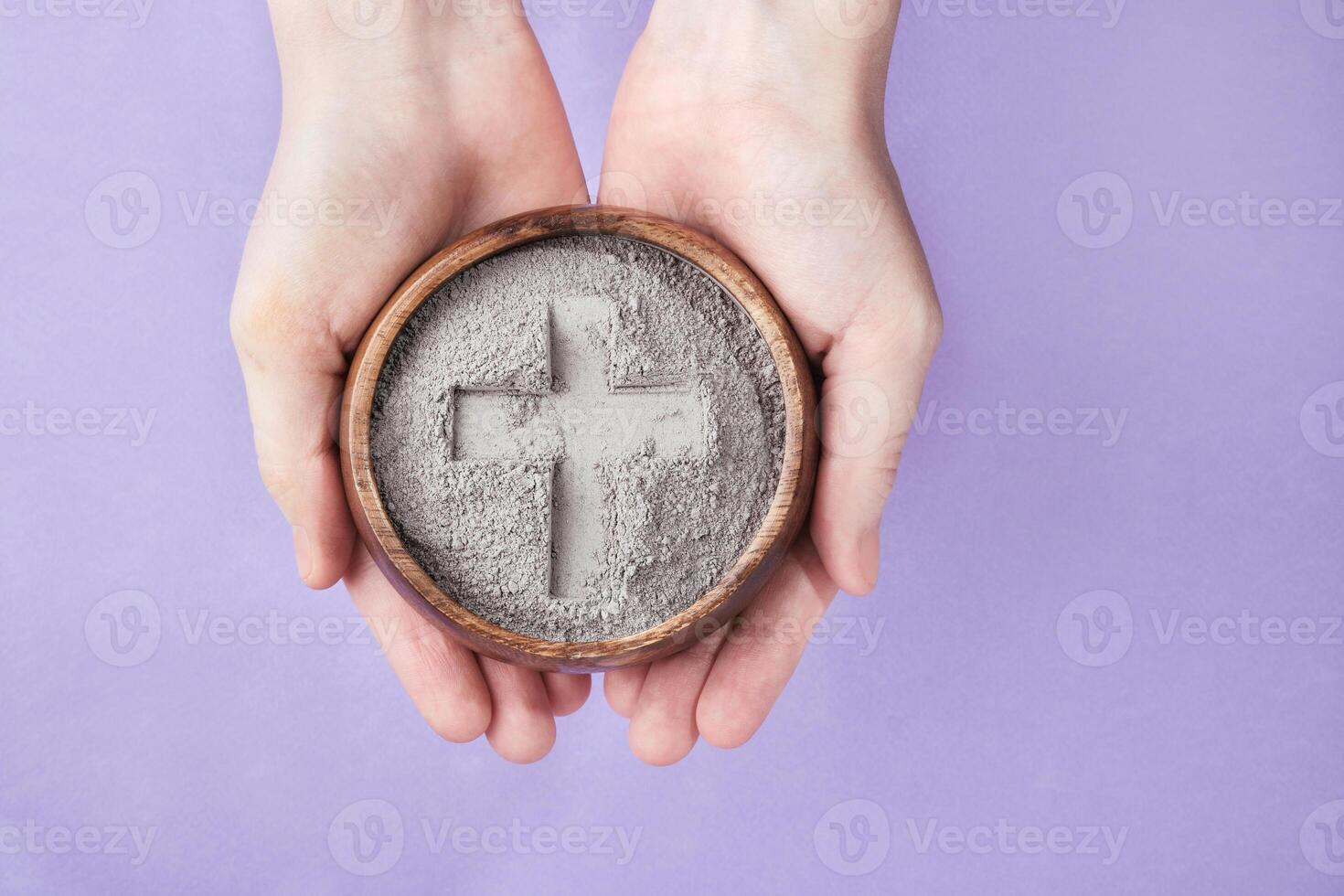 Hands with gray ash bowl on purple background. Ash Wednesday photo