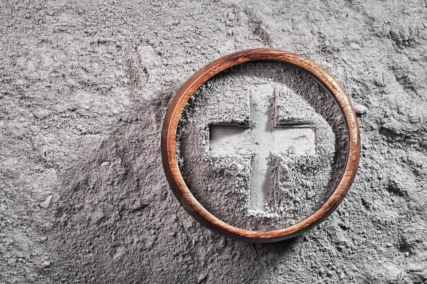 Cross imprint in gray ash bowl on ash background. Ash Wednesday photo