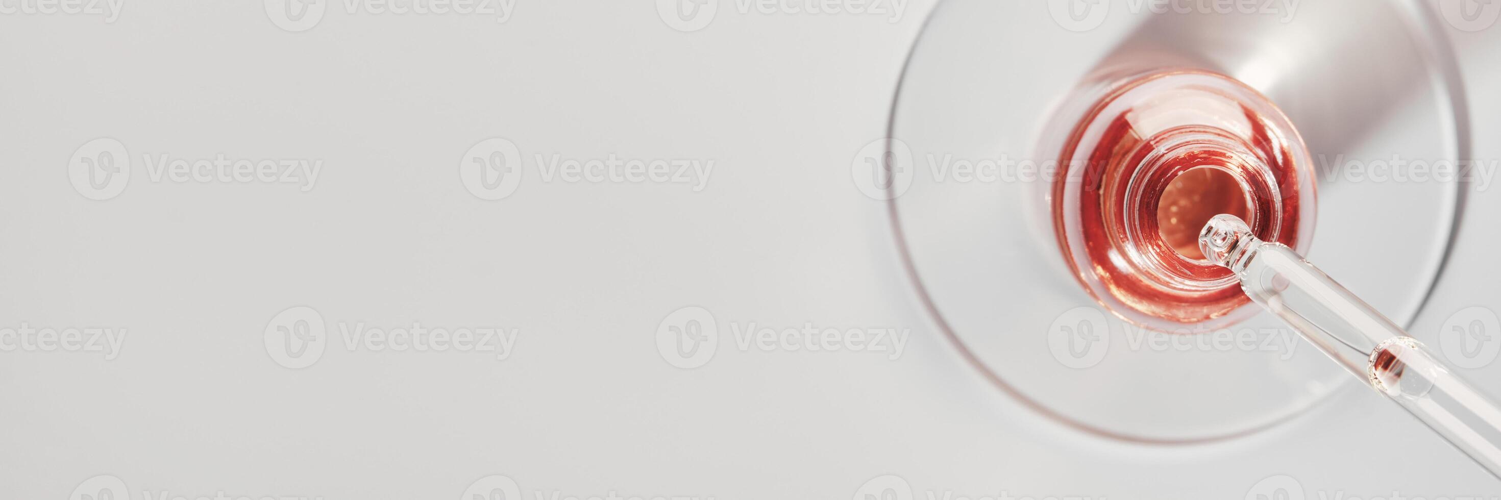 Serum bottle and pipette in petri dish on grey banner. Pink cosmetic product photo