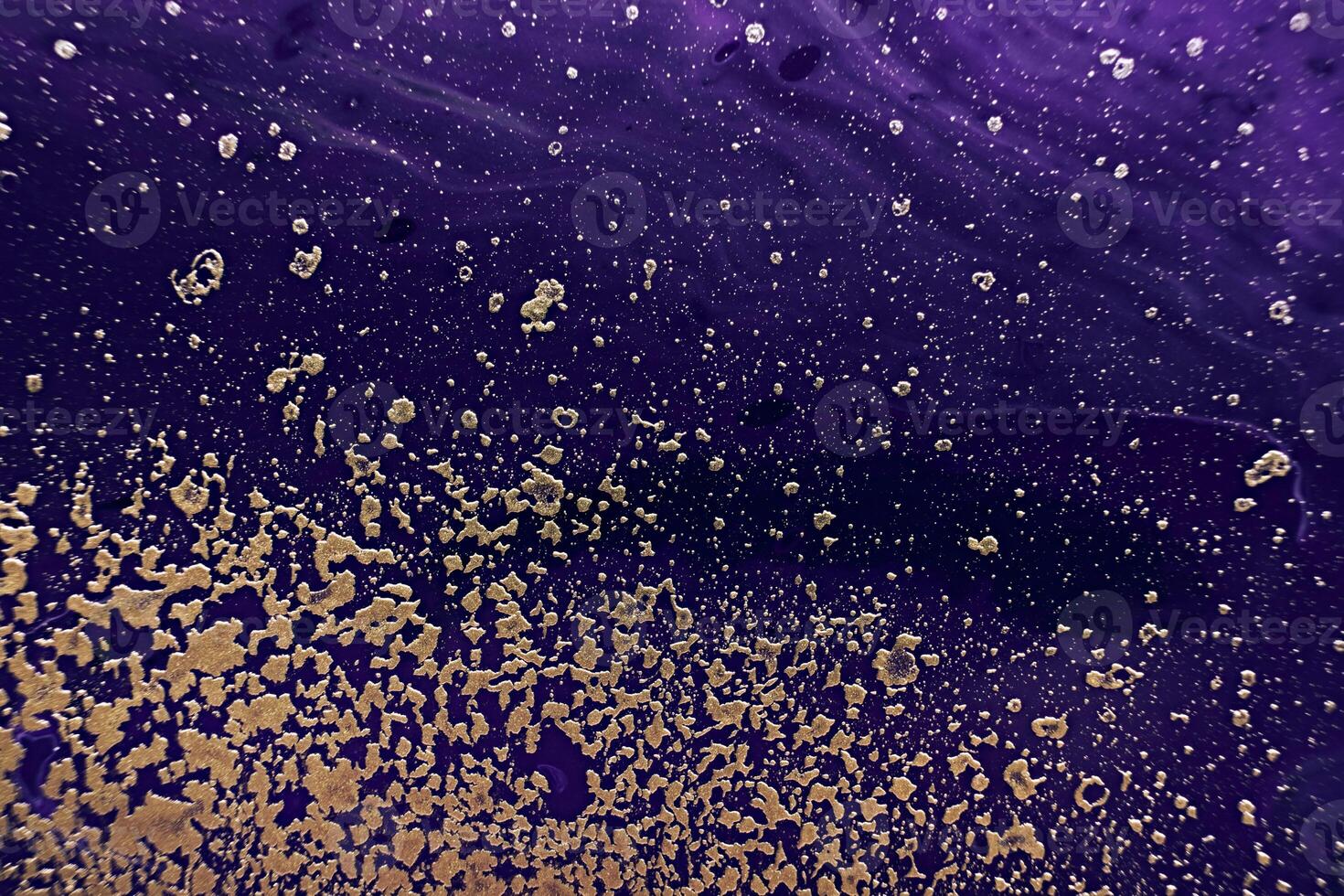 Golden spray particles and purple waves on black background. Marble effect background or texture photo