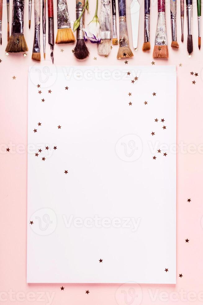 Drawing album frame, row brush and golden stars on pink background photo