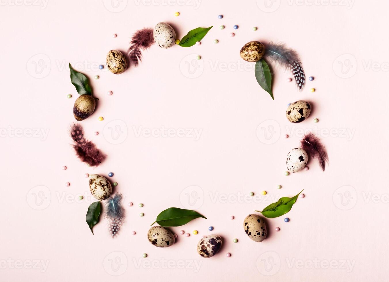 Easter nature wreath frame of quail eggs, green leaves and feathers photo
