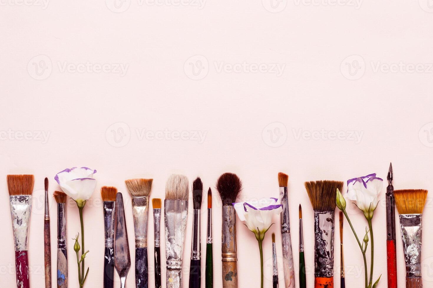 Art Creativity pink background. Row of different brushes and flowers photo