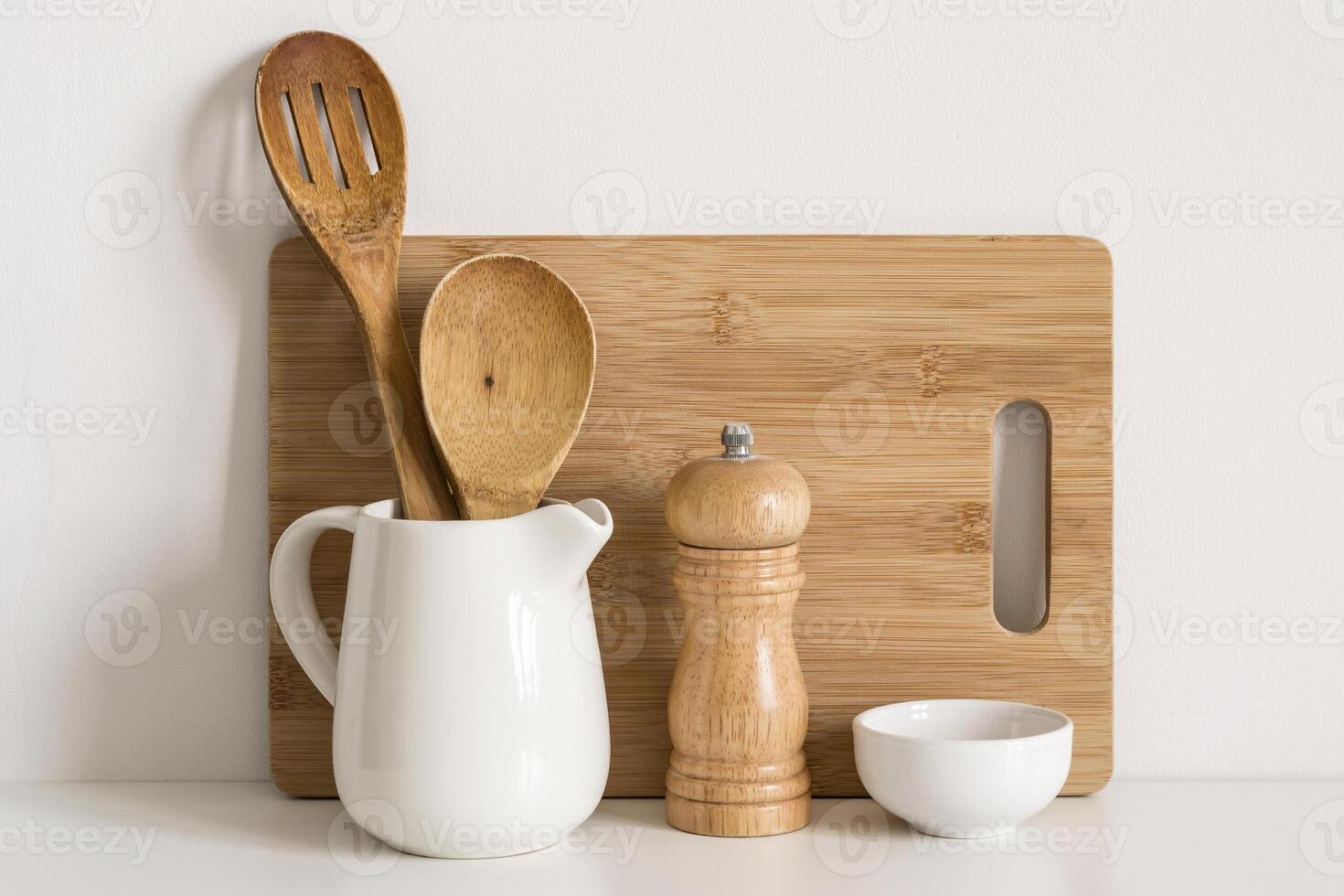 Kitchenware cutting board, spoons and spice mill on table wall background photo
