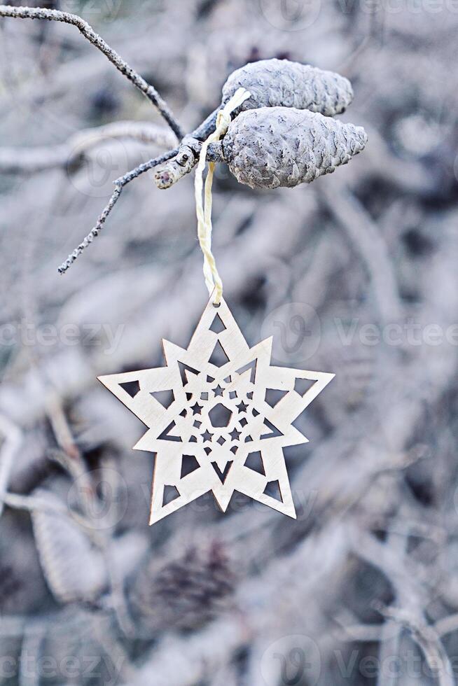 Traditional scandinavian Christmas decorative wooden snowflake on the blue natural background with branches of tree. Christmas greeting card in minimal style photo