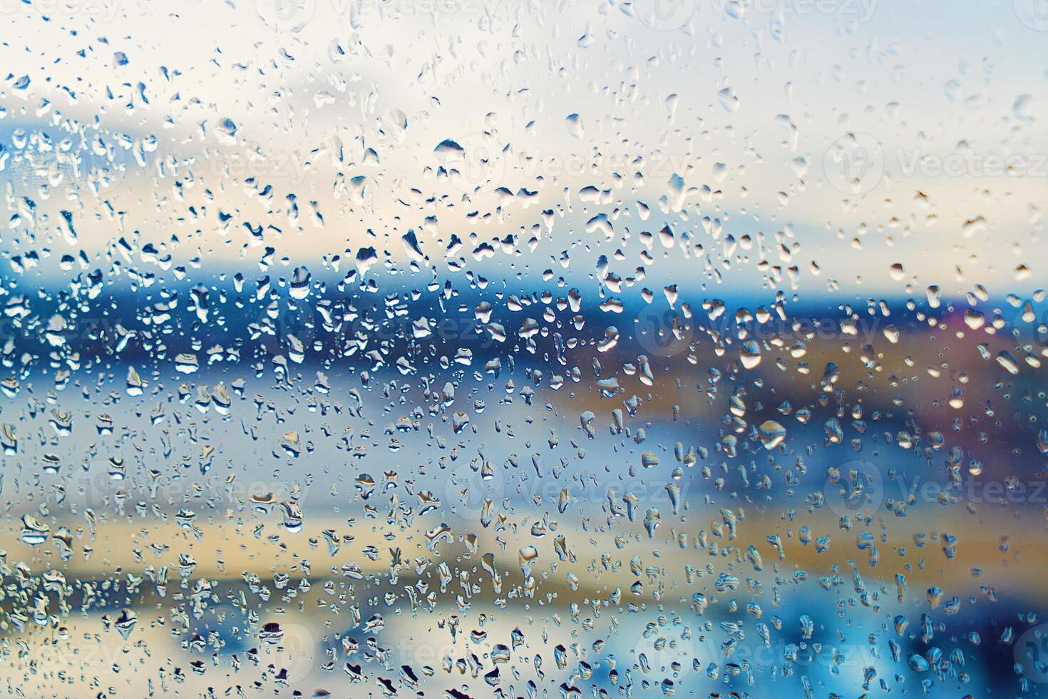 Abstract blurred background street outdoor behind wet window with rain drops, blurred street bokeh. Concept of autumn weather and rainy season, copy space photo