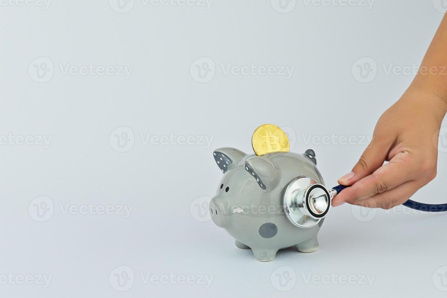 Concept of financial bitcoin diagnostics and crypto currency exchange rate forecasting. Funny piggy bank, bitcoin and stethoscope on gray background photo