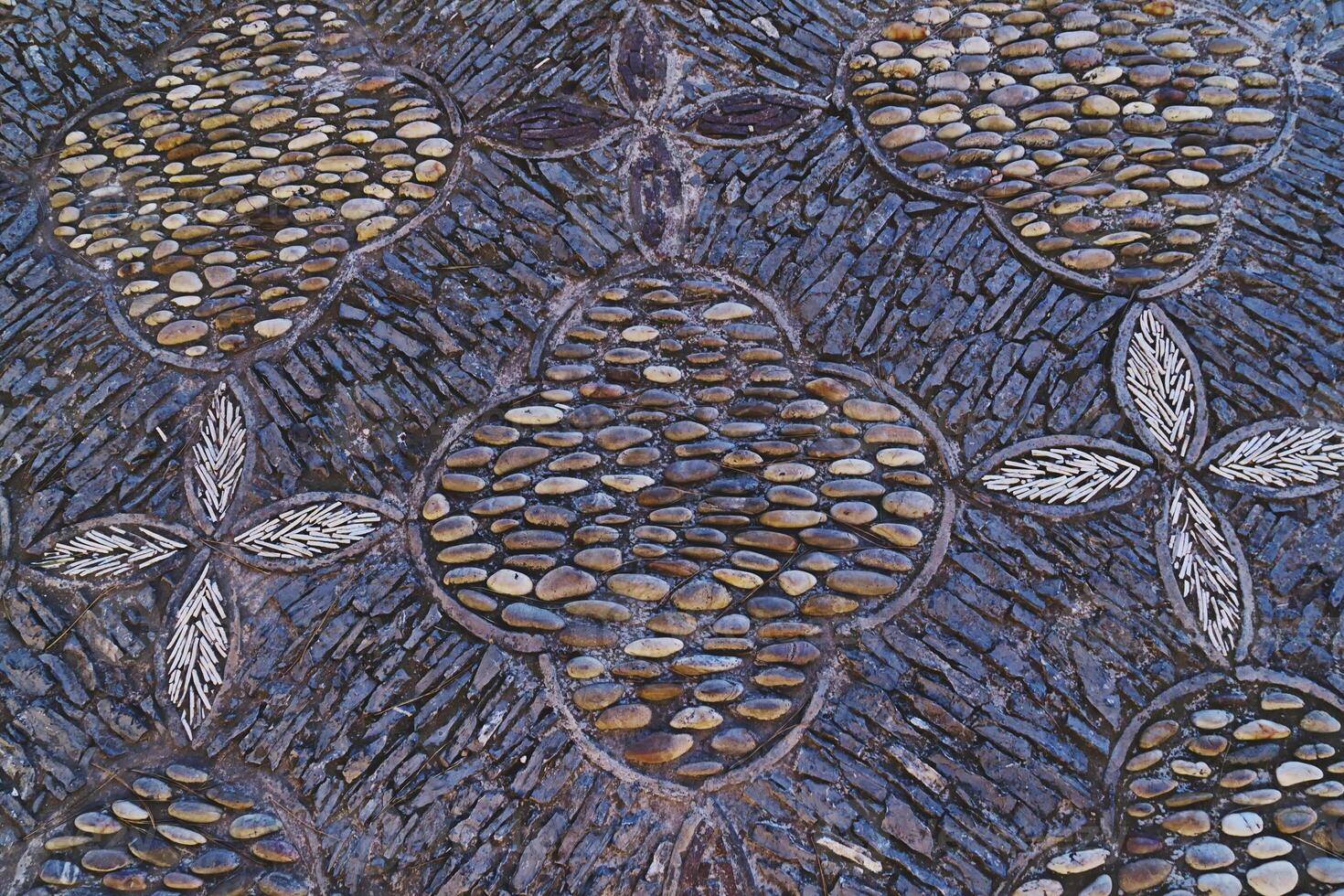 Ancient patterns laid out of pebbles in garden on road surface photo