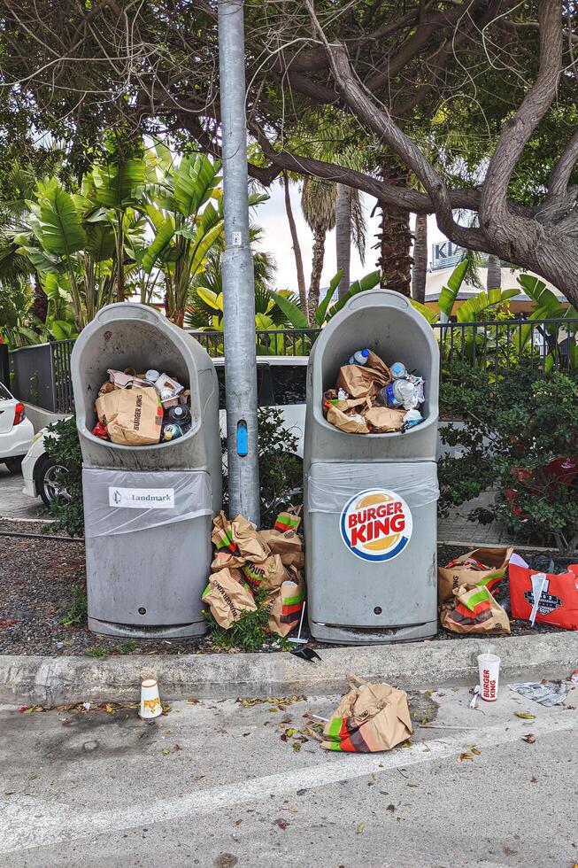 Qormi, Malta - March, .2024. Overfilled fast-food Burger King trash bins with litter in public parking area photo