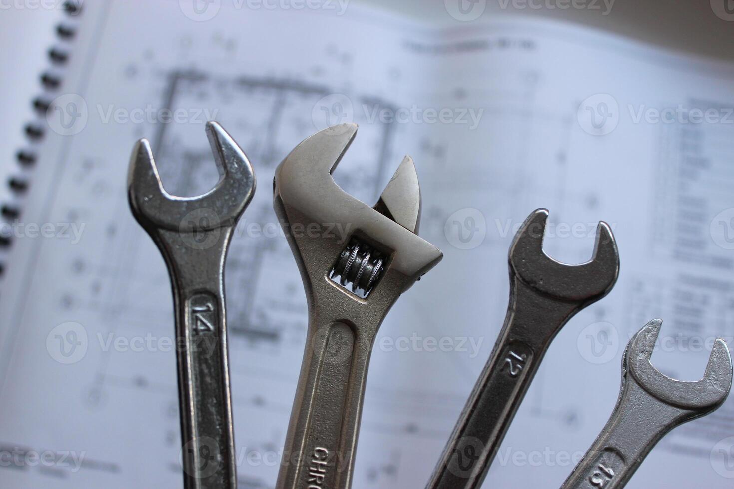 Hex spanners and adjustable wrench over defocused paper drawing of a house rooms and premises photo