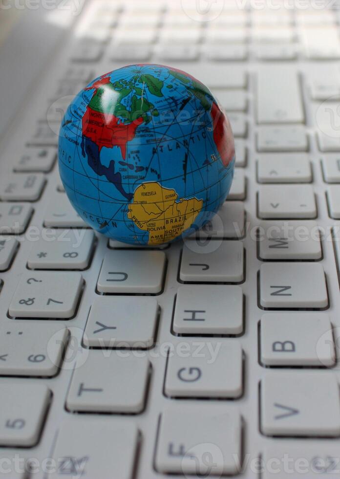 Closeup photo of globe with mapped North and South America continents lying on computer keys angle view