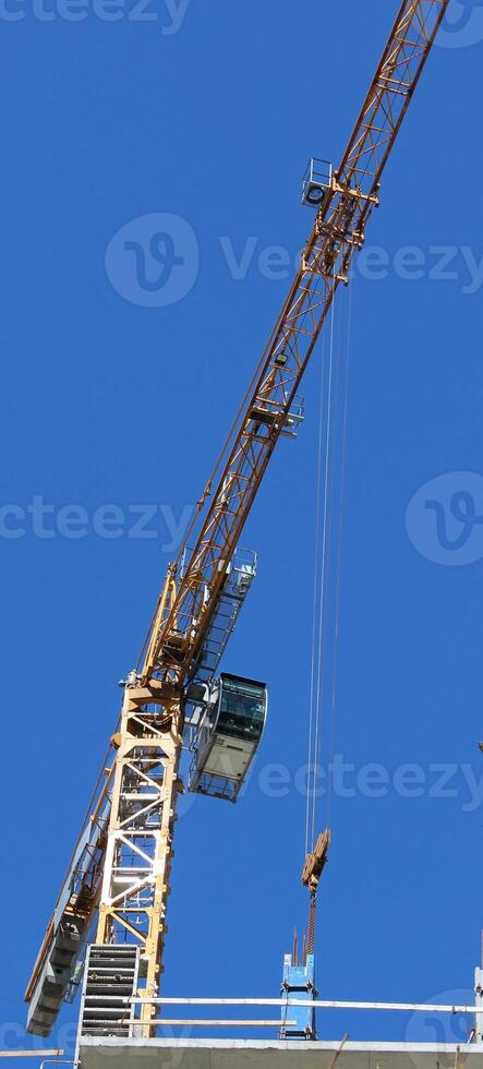 Operator Cabin And Long Boom Of High Rise Construction Crane On Blue Sky Background Vertical Stock Photo