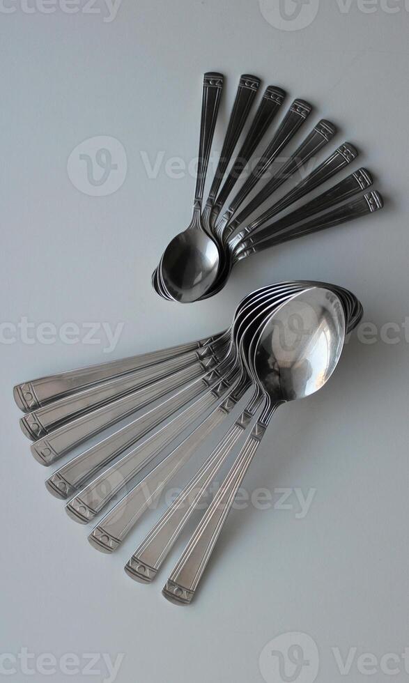 Tablespoons And Teaspoons From One Cutlery Set Laid Out In Form Of Wings. Concept Photo For Table Setting Backgrounds
