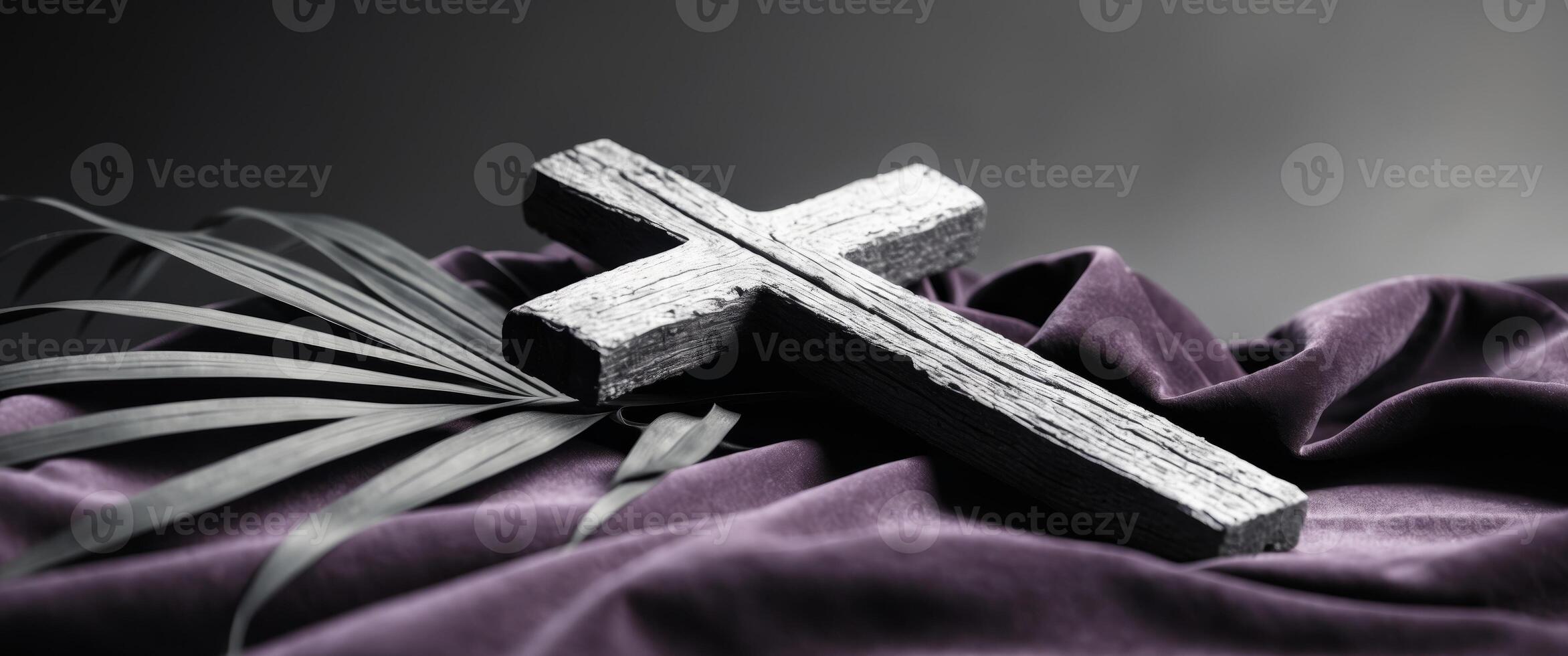 Wooden cross with palm leaf on the background of a purple cloth. photo