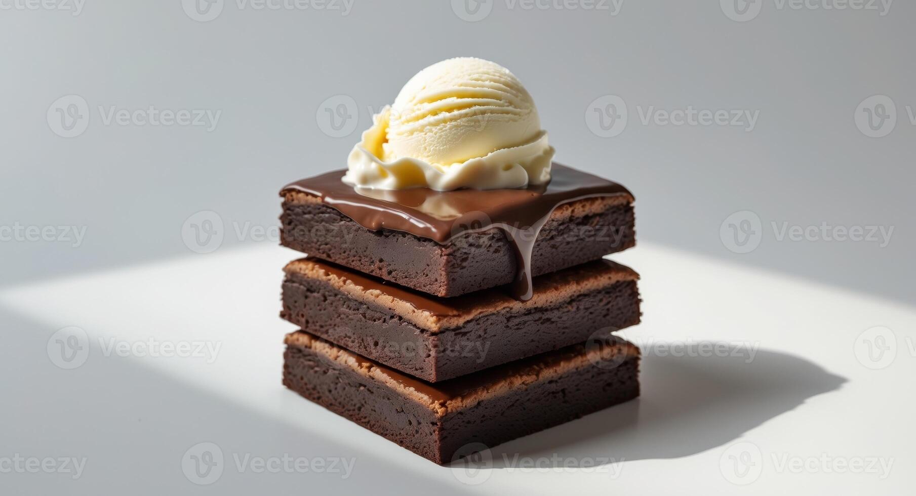 A decadent brownie stack topped with melted chocolate and a scoop of vanilla ice cream on top. photo