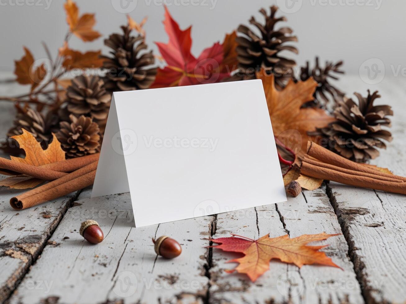 Autumn leaves and acorns on a wooden table with a blank card photo