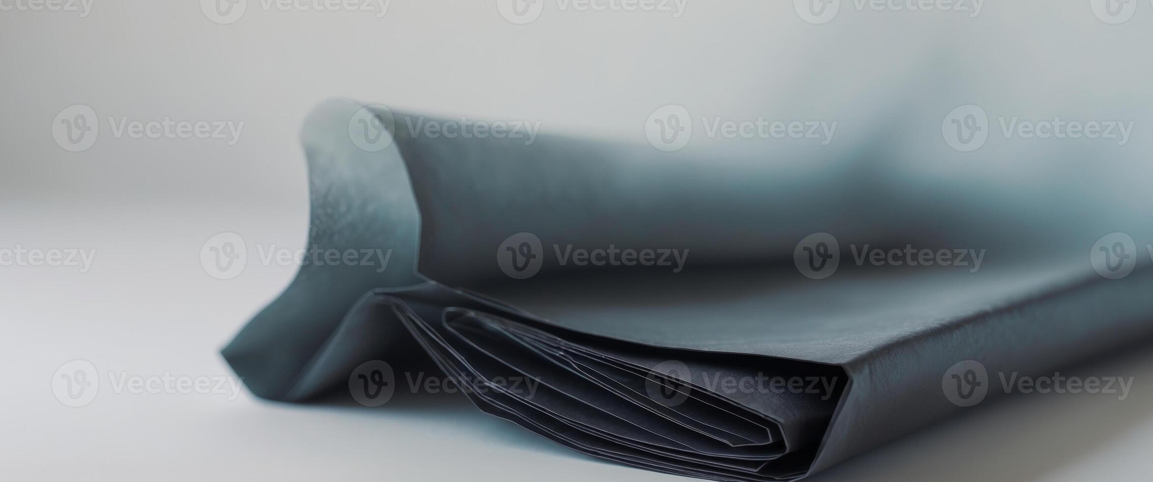 A folded piece of black cloth on a white surface photo