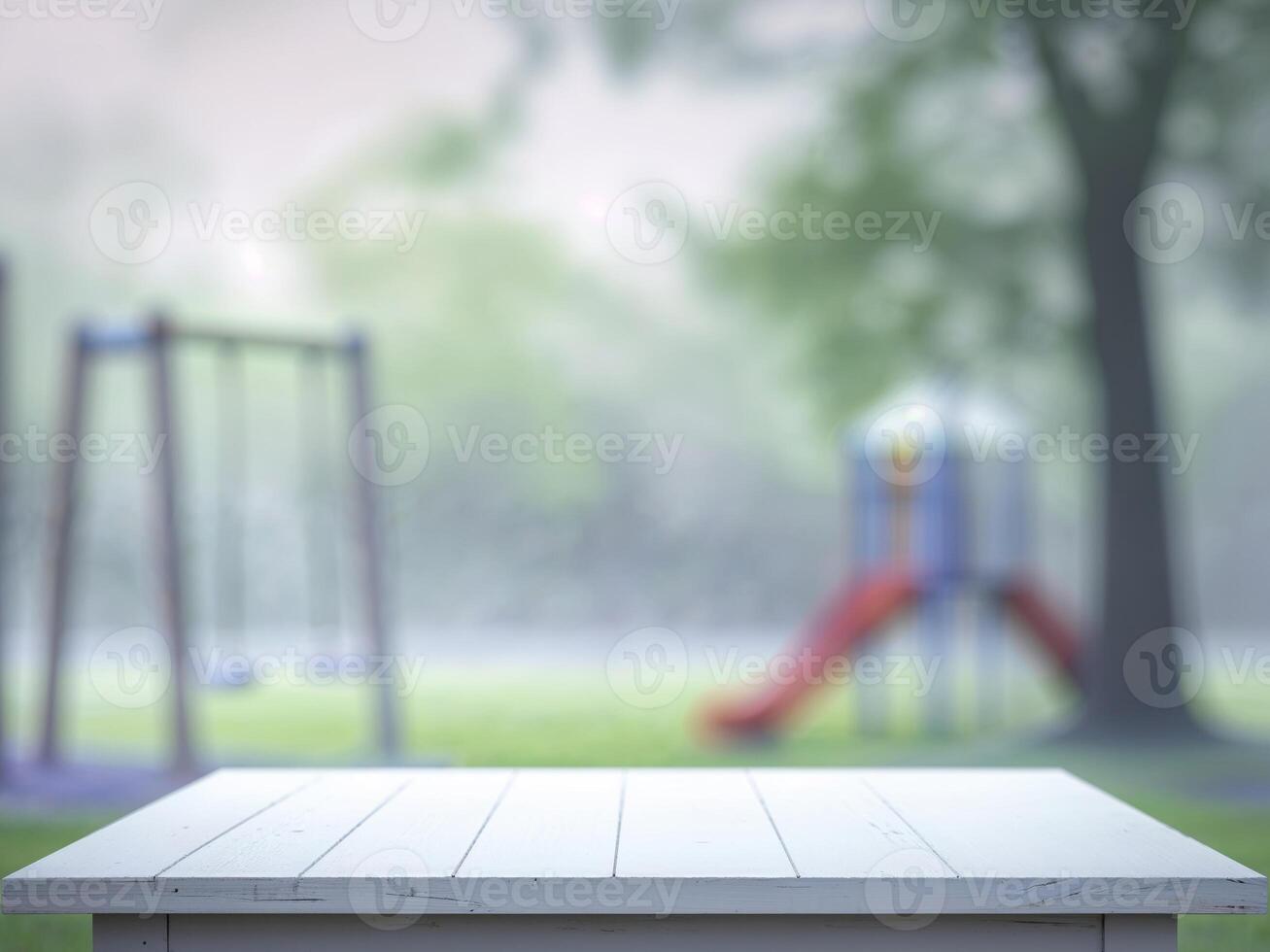 Empty wooden table in the park with playground and swings photo
