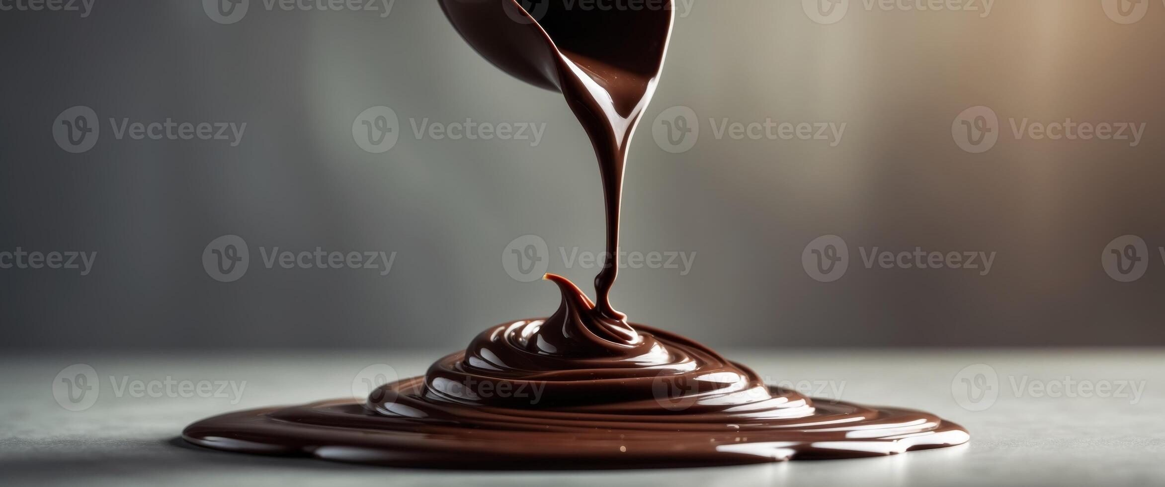 Melted dark chocolate pouring and creating swirls on a surface. photo