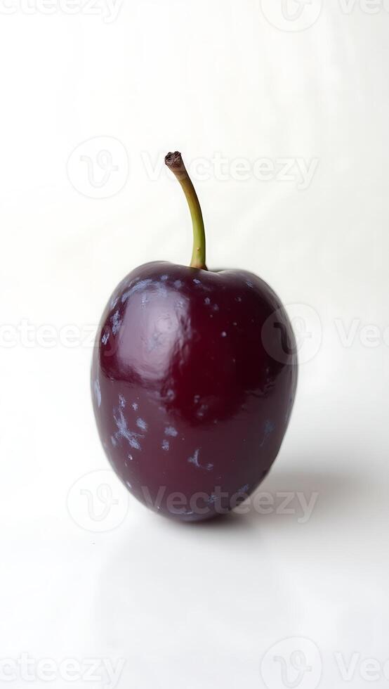 Closeup of a glossy purple fruit with a small stem against a white background photo