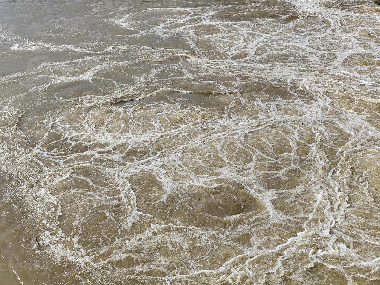 Fast-Flowing Brown Water with Dynamic White Bubbles photo