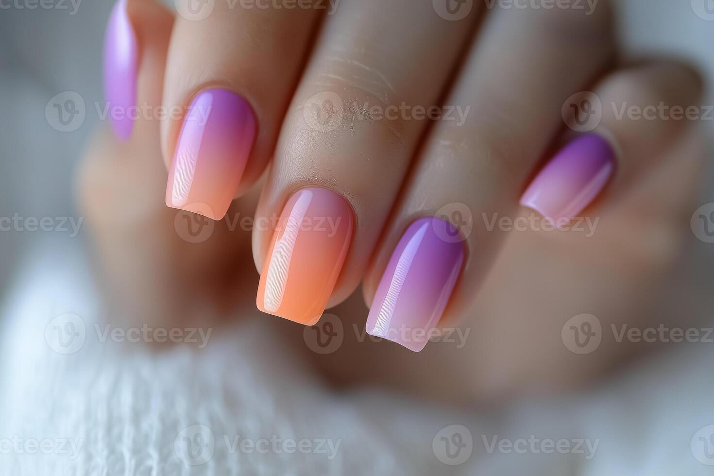 A woman's hand with purple and orange ombre nails photo