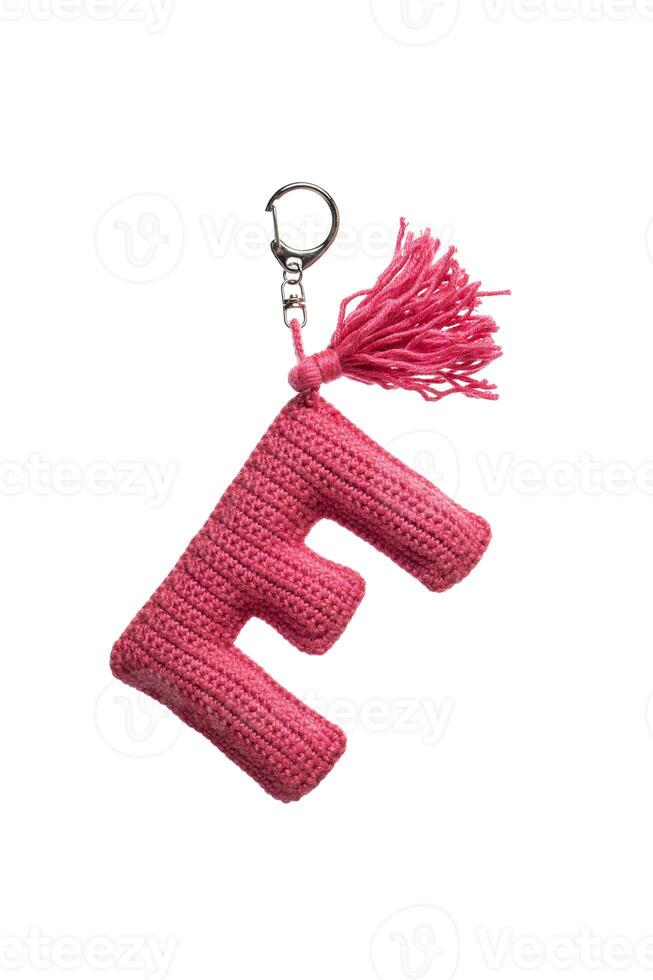 A pink crocheted keychain in the shape of the letter E with a metal clasp and a tassel, isolated on a white back photo