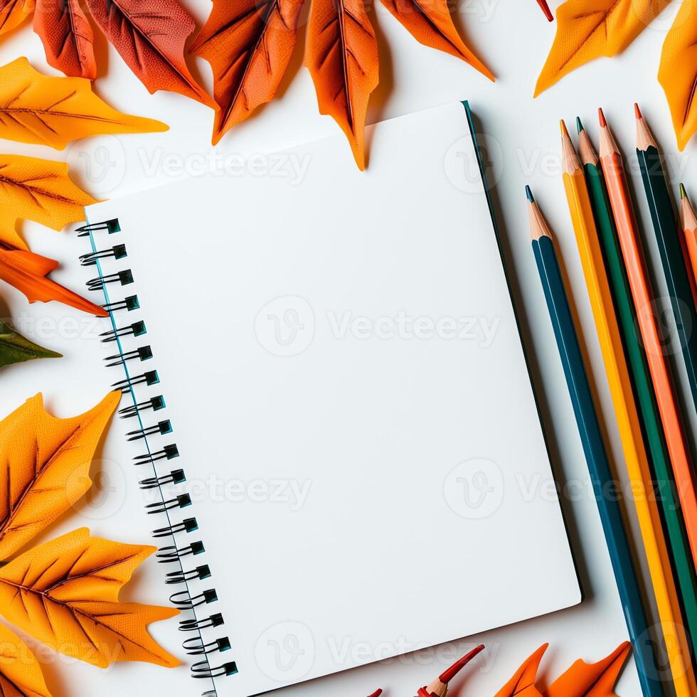 Colorful autumn leaves surround a blank notepad and vibrant colored pencils. Perfect for creative projects, journaling, or crafting in a cozy fall setting. photo