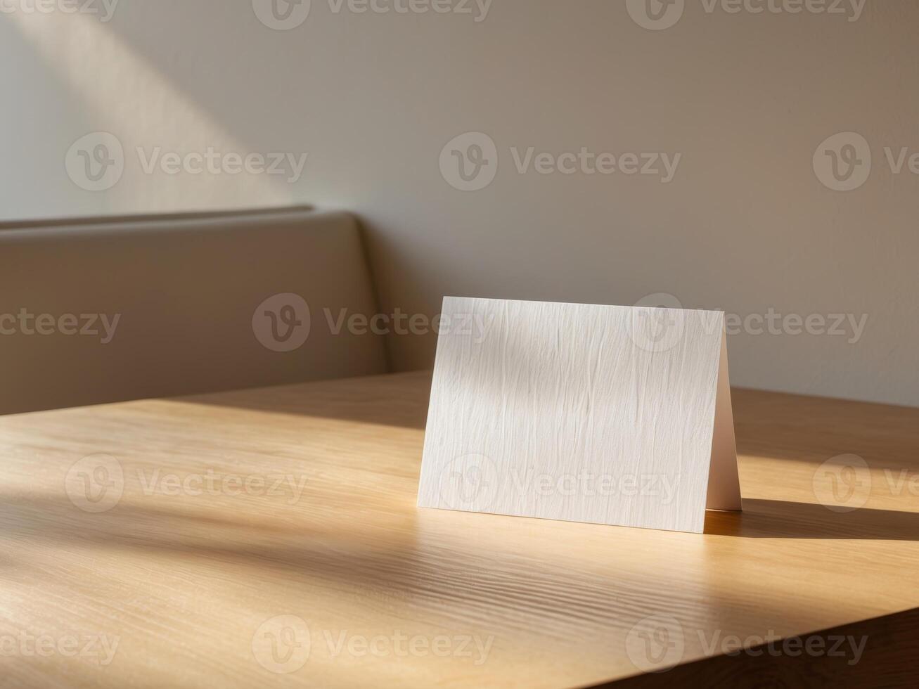 A white card on a wooden table in front of a window photo