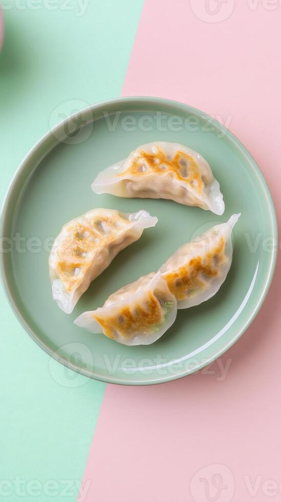 Delicately sliced cabbage and pork dumplings served on a mint green plate against a pastel backdrop photo