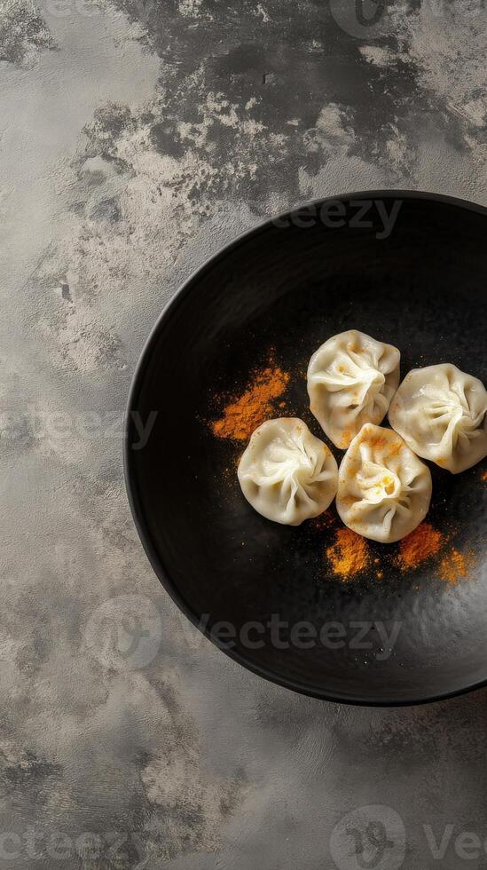 Traditional momo dumplings served with vibrant spices on a deep black plate photo