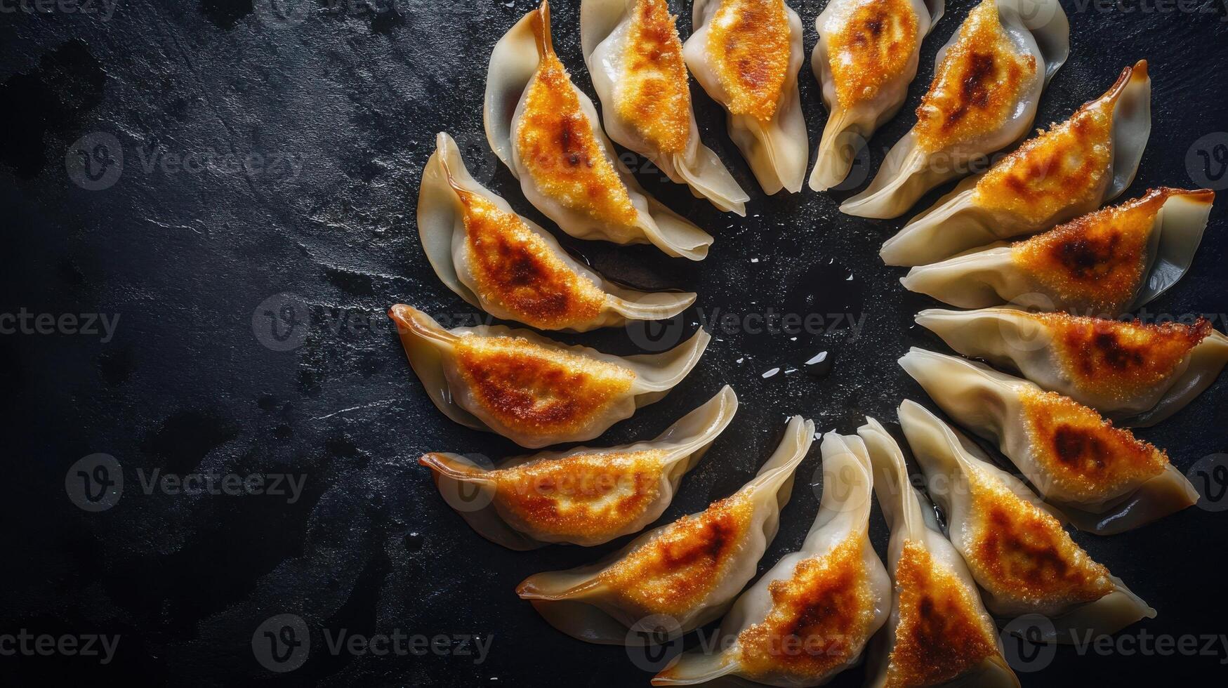 Modern presentation of pan-seared dumplings arranged in a circular pattern on a dark surface photo