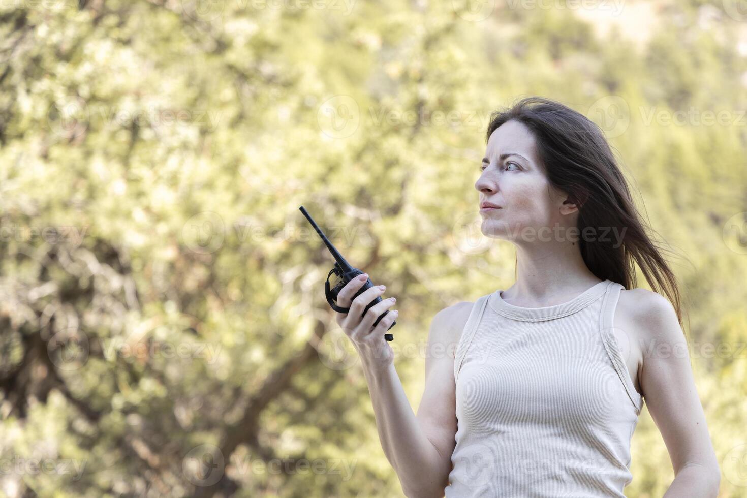 Woman holding two-way radio for hiking. Walkie-talkie in hand photo