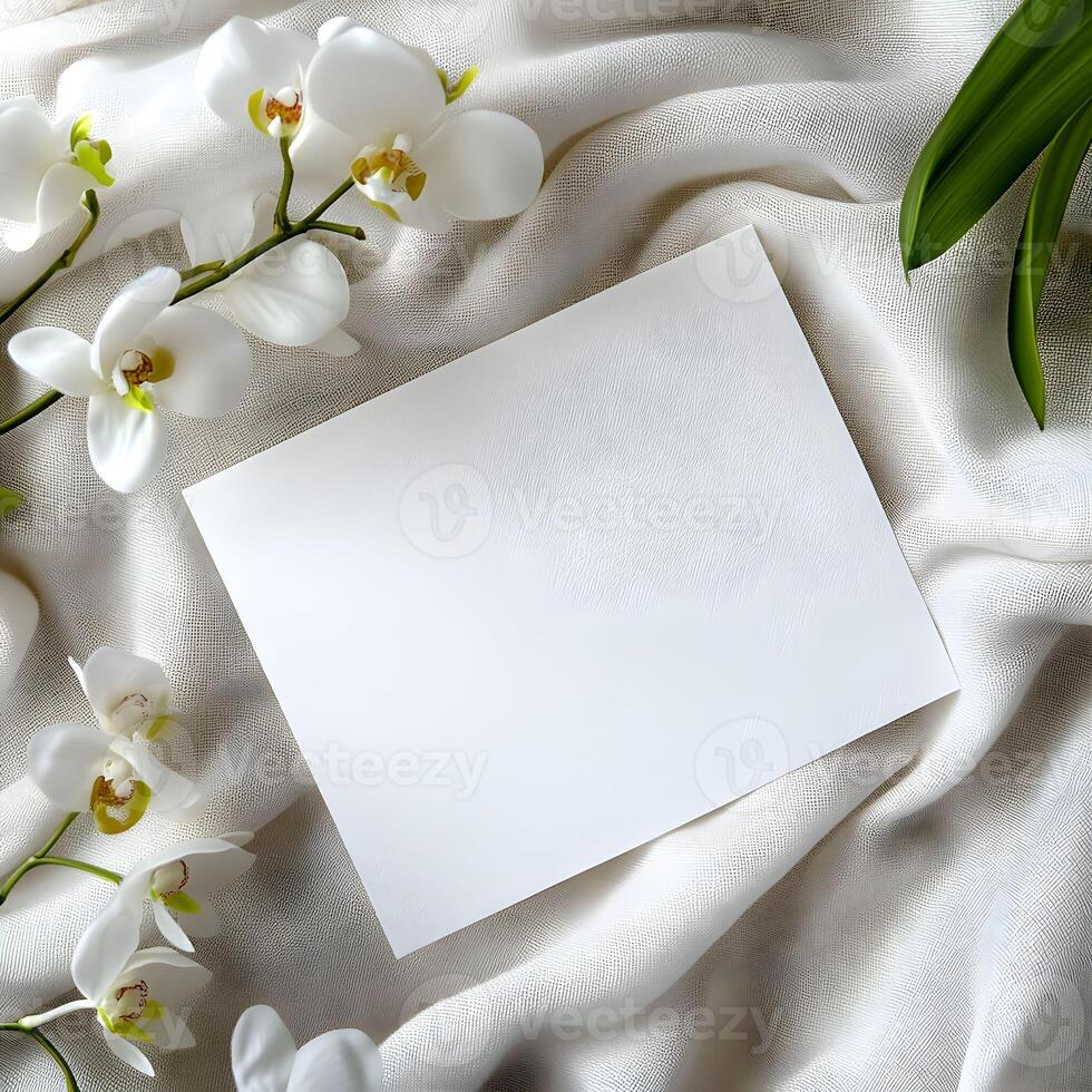Elegant white blank card for wedding invitation mockup surrounded by delicate white orchids on soft beige fabric conveys a sense of calm and simplicity suitable for various occasions and messages photo