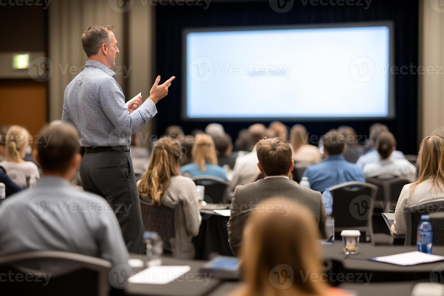 Speaker presenting at conference. audience listens, projector screen shows presentation, ideal for business or education photo