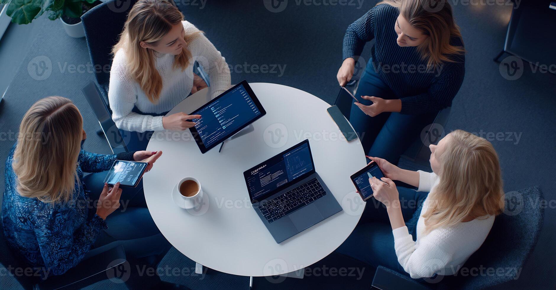 Four women collaborating on a project using tablets and laptops. photo