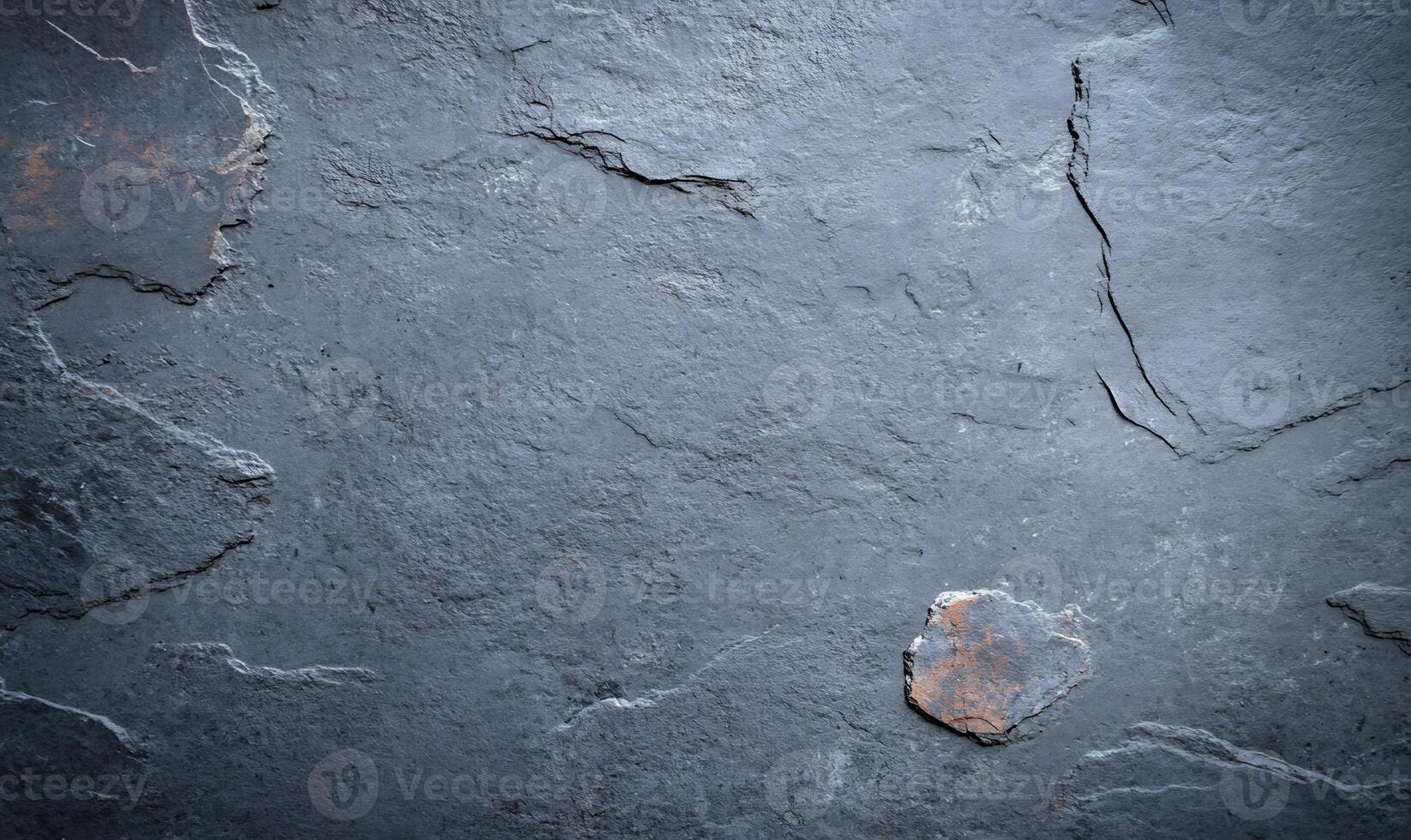 Dark gray slate stone slab surface texture with natural patterns and a small rusty spot. photo