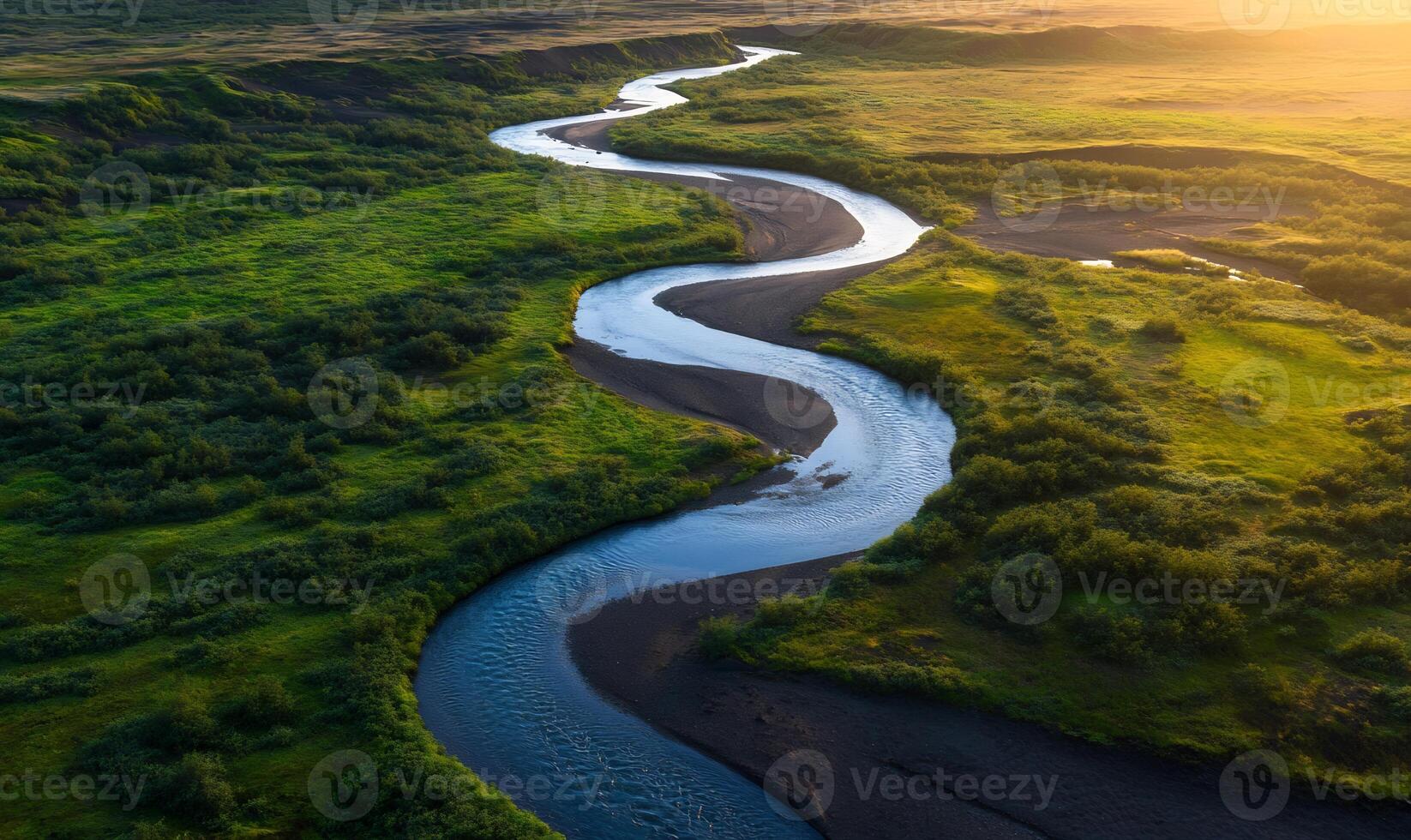 Aerial view of a meandering river flowing through lush green landscape at sunset. photo