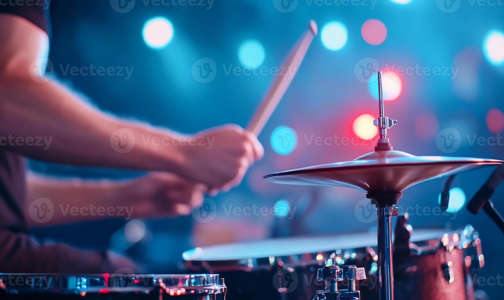 Drummer playing drums on stage with bright lights. photo